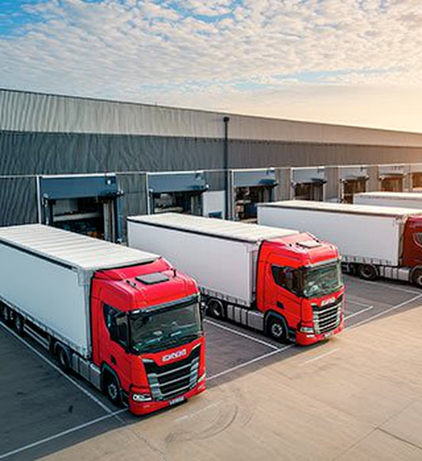 Fleet of delivery trucks at warehouse loading bays